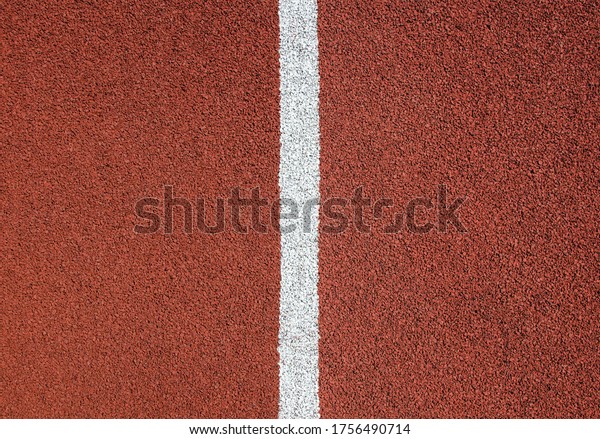 Red rubber running track texture close up. White\
divider line in the center.