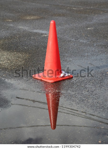 Red Safety Cone on the Wet\
Ground