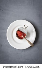 Red Salmon Caviar In An Open Metal Tin Can On A White Plate On Gray Background