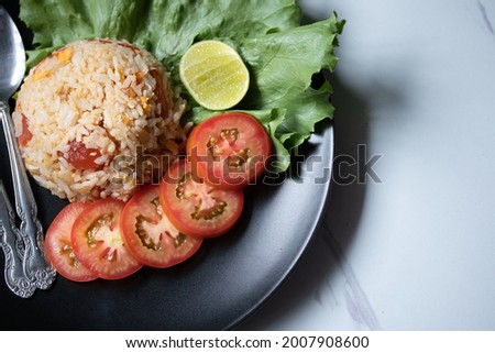 Red salted egg fried rice with vegetables in black plate