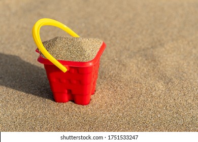 Red Sand Castle Bucket On A Sand Background. Minimal Summer Vacation Concept.