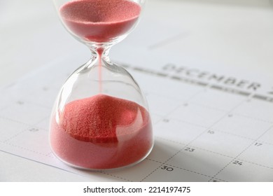 Red Sand Running Through Bulbs Of Hourglass, On December Calendar, Measuring Passage Of Time, End Of Year, Time Running Out Concept