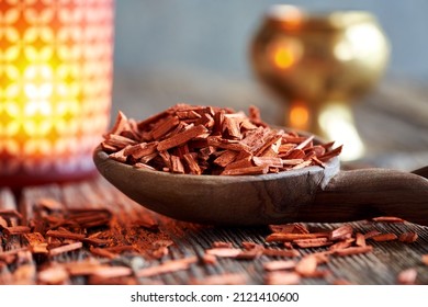 Red Sandalwood On A Wooden Spoon, With A Candle And An Incense Burner In The Background