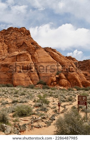 Red sandstone cliffs and trail sign near Jenny's Canyon Trail at Snow Canyon State Park, Utah