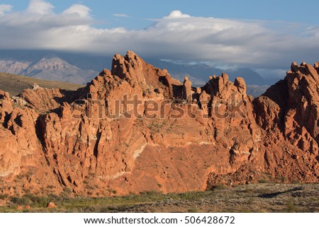 Red sandstone ridge forming part of the Virgin anticline along the Virgin river in Southern Utah.  Pine Valley mountain and clouds in the background and open desert in the foreground.