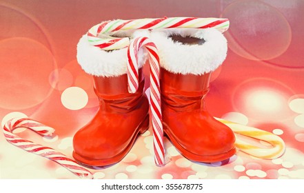 Red Santa Claus Boots, Shoes With Colored Sweet Lollipops, Candys. Saint Nicholas Boots With Presents, Gifts, Red Bokeh Background.