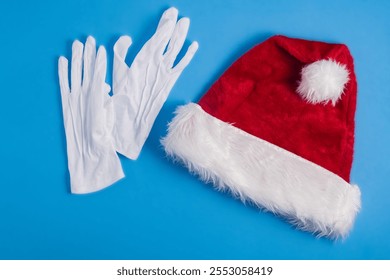 Red Santa hat and white gloves on a blue background - Powered by Shutterstock