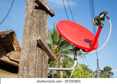 red satellite dish installed on wooden stake, Thailand
