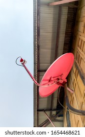 The Red Satellite Dish For Receiving Satellite TV Signals 20 Is Located On A Wooden House Used For Watching Satellite TV Programs With Digital Clarity.