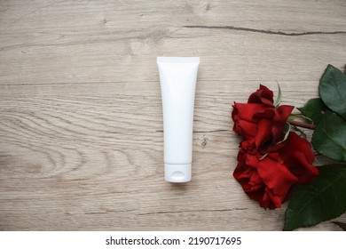 Red Scarlet Rose Flower Cream Tube Cosmetic On Wooden Background With Red Roses, Top View, Copy Space, Mockup.