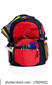 A Red School Back Pack Or Book Bag Overflowing With School Supplies Including, Notebooks, Pens, Pencils, Rulers And Glue