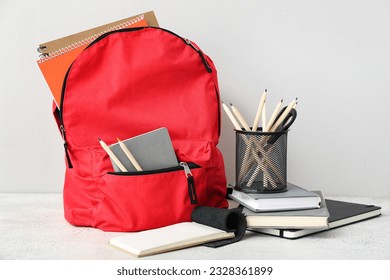 Red school backpack with notebooks, color pencils and scissors on white grunge table near wall - Powered by Shutterstock - Get 15% off with code: PIKWIZARD15
