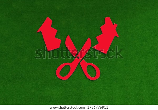 Red scissors that cut the house in two on a\
green background. Division of\
property.