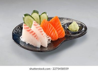 Red sea bream sashimi or Tai sashimi and Salmon sashimi served with wasabi in black plate on grey background. - Powered by Shutterstock