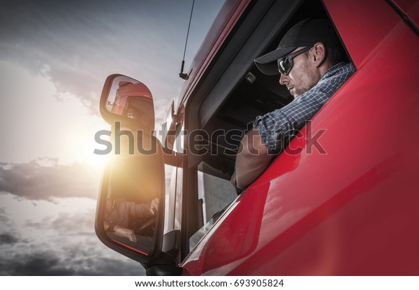 Red Semi Truck. Caucasian Truck Driver
Preparing For the Next Destination.
