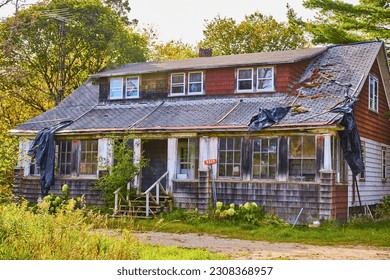 Red shingles falling off old abandoned house and black tarp broken shingles   wood steps