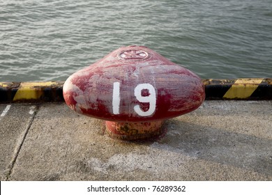 A Red Ship Bollard By The Dock With The Number 19 Painted On It