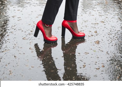 Red shoes high-heeled on wet asphalt. The woman costs on wet asphalt.