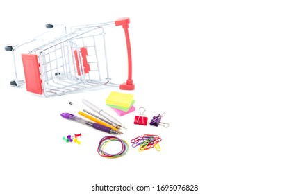 Red Shopping Cart Or Trolley And Office Stationery (pen,pencil, Note Pad, Leather Clip,pin, Rubber)  Isolated On White Background. Online Shopping Concept.