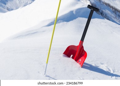 Red Shovel And Graduated Probe For Avalanche Safety In Powder Fresh Snow. Winter Season In The Italian Alps.