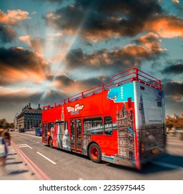 Red sightseeing tour bus across London at sunset. Tourism concept. - Shutterstock ID 2235975445