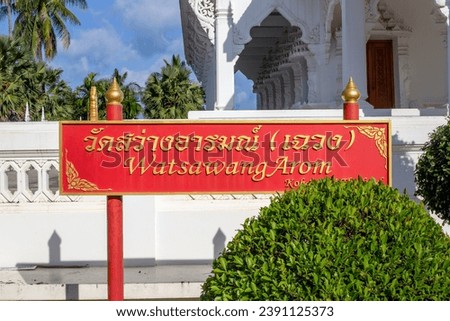 Red sign near the White Buddhist Temple with the inscription Wat Sawang Arom.