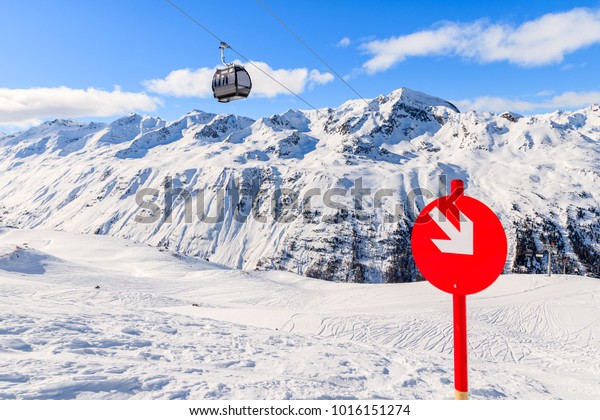 Red sign on ski slope and gondola car on lift in\
beautiful mountains in winter season in Hochgurgl-Obergurgl ski\
area, Tirol, Austria