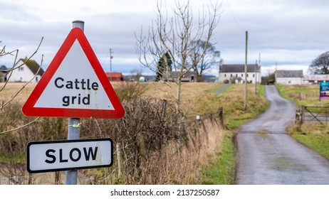 Red sign warning cattle grid ahead on a farm and to slow down