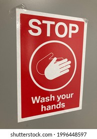 Red Sign With „stop Wash Your Hands“ In White On It. And Symbol Of Two Hands Washing Each Other