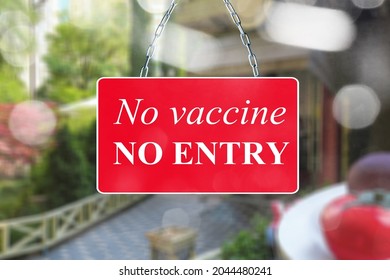 A Red Sign In The Window Of A Shop Displaying The Message Text No Vaccine, No Entry.