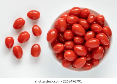 Red small cherry tomatoes in a bowl on white background, top view - Powered by Shutterstock