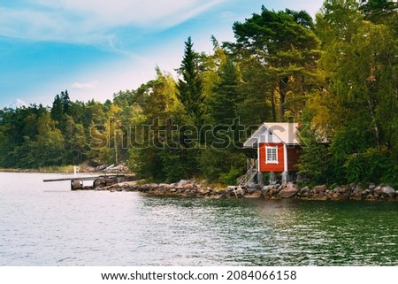 Red Small Finnish Wooden Sauna Log Cabin On Island In Autumn Season.