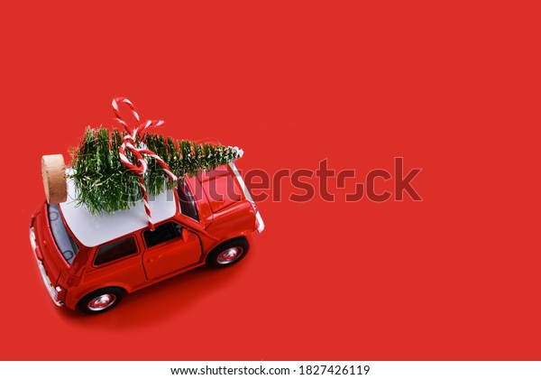 Red small\
retro toy car with gift on the roof on red background. Delivery.\
New Year and Christmas, Sale\
concept.