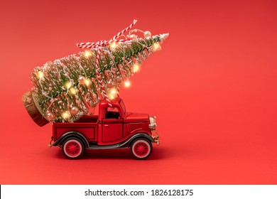 Red small retro toy truck with sparkling Christmas tree lights on truck body on red background. Delivery, christmas, New Year concept. Copy space, selective focus. - Powered by Shutterstock