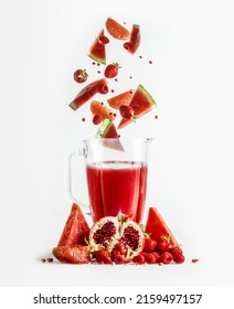 Red smoothie in blender with falling ingredients: grapefruit, watermelon, pomegranate, strawberries and raspberries. Healthy refreshing drink with vitamins. Levitation concept. Front view.