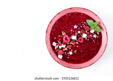 Red Smoothie Bowl Topped With Pecan, Freeze Dried Raspberry, Coconut Cubes, Microgreen And Sugar Sprinkles On The White Table. Top View. Healthy Dessert