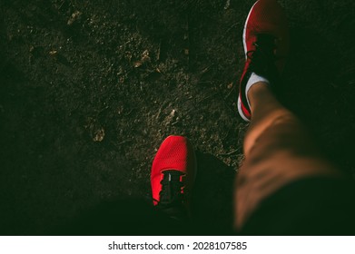 Red sneakers on male athlete's feet standing on dirt road in early morning.  - Powered by Shutterstock