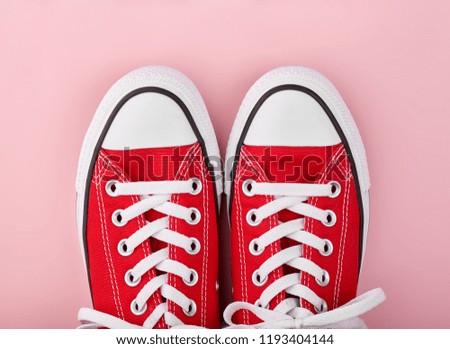 Red sneakers on pink background with copy space. Youth shoes.