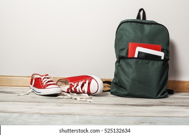 Red sneakers with school bag on wooden background