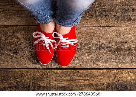 red Sneakers shoes walking on Dirty wooden top view , Canvas shoes walking on wooden