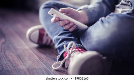 Red Sneakers. The Teenager With A Smartphone.