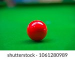 Red snooker ball on green table background