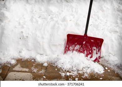 Red Snow Shovel In A Snow Bank On Pavement