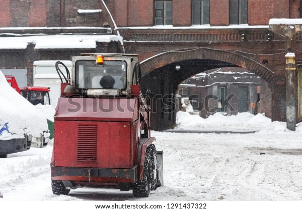 Red snowblower clears snow from the street after\
a big snowstorm, back view/ snowy winter, snowthrower, during a\
blizzard, snow removal car, equipment for cleaning city roads,\
winter concept.