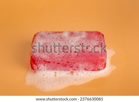 Red Soap Bar, Body Care Cosmetic, Fruit Flavored Soapy Detergent, Solid Shampoo, Red Translucent Glycerin Soap on Yellow Foamy Background