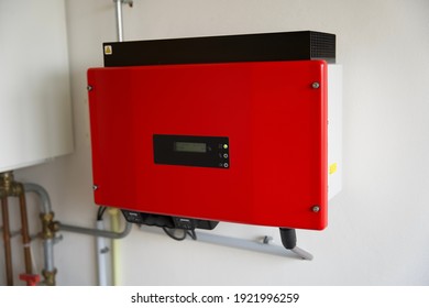 Red Solar Power Inverter Mounted On A White Wall