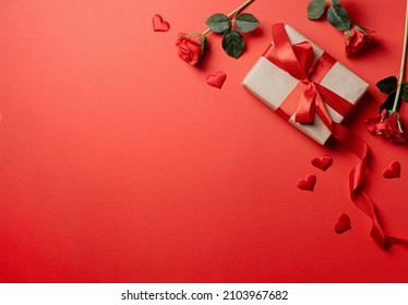 Red solid background with red hearts, gifts and confetti. The concept of Valentine Day.