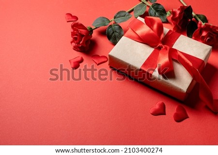 Red solid background with red hearts, gifts and confetti. The concept of Valentine Day.