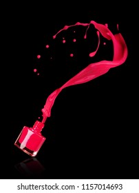 Red splash of nail polish poured from bottles on black background