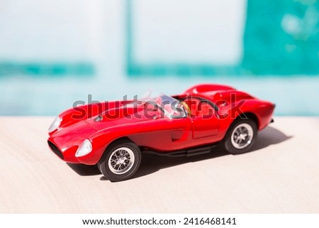 Red sport model car on swimming pool edge with space on blurred background, outdoor day light